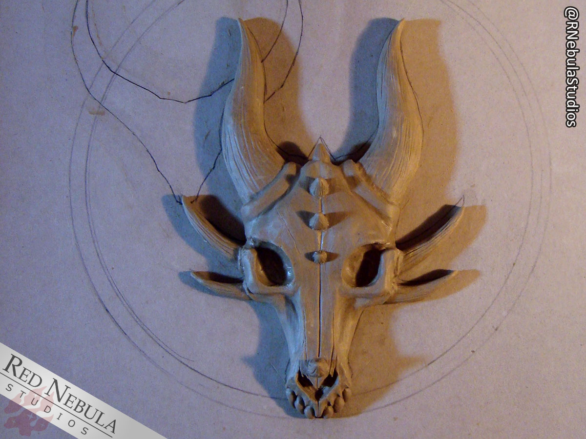 A sculpted dragon skull wall plaque in clay.