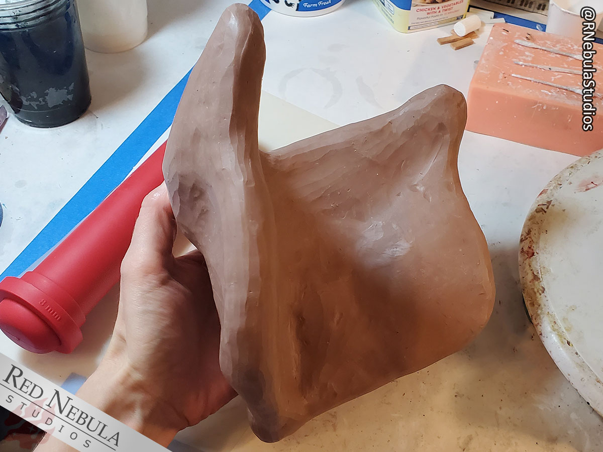 The oil-based clay layer on the owl mask now covers it completely, front and back, and has been smoothed out.