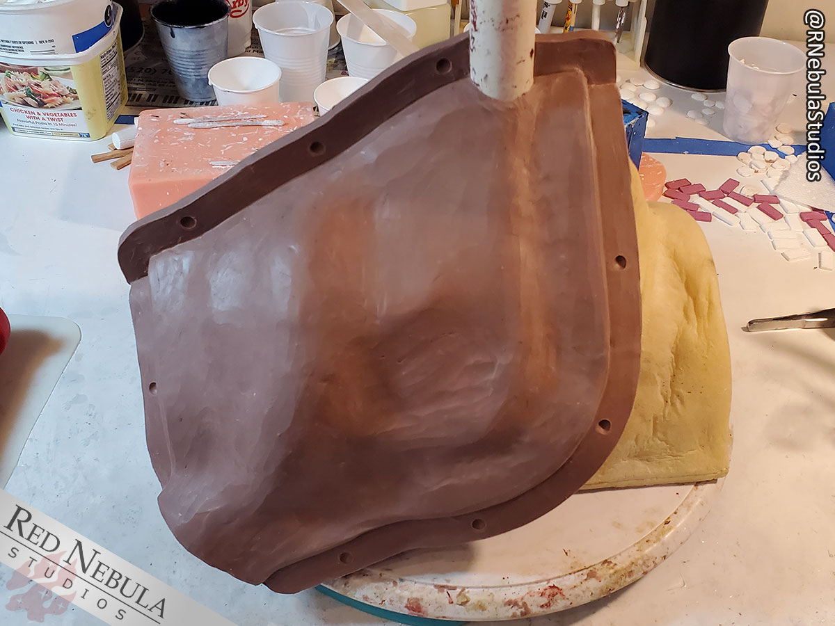 An additional flange of clay is added where the mother mold will wrap around the silicone. A silicone pour spout is added, along with keys.